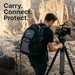 Videographer wearing the Targus Drifter backpack while operating a camera on a tripod at a canyon overlook. Text overlay reads: 
